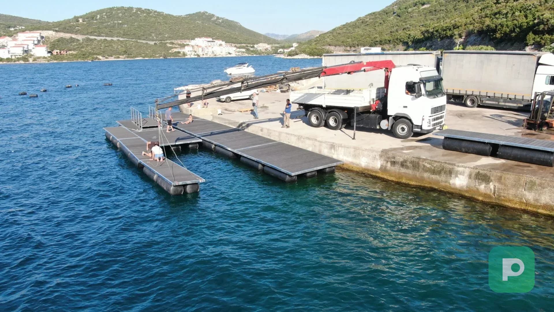 Montaža Plastopex plutajuće marine sa PEHD pontonima na morskoj obali uz pomoć kamiona sa dizalicom.