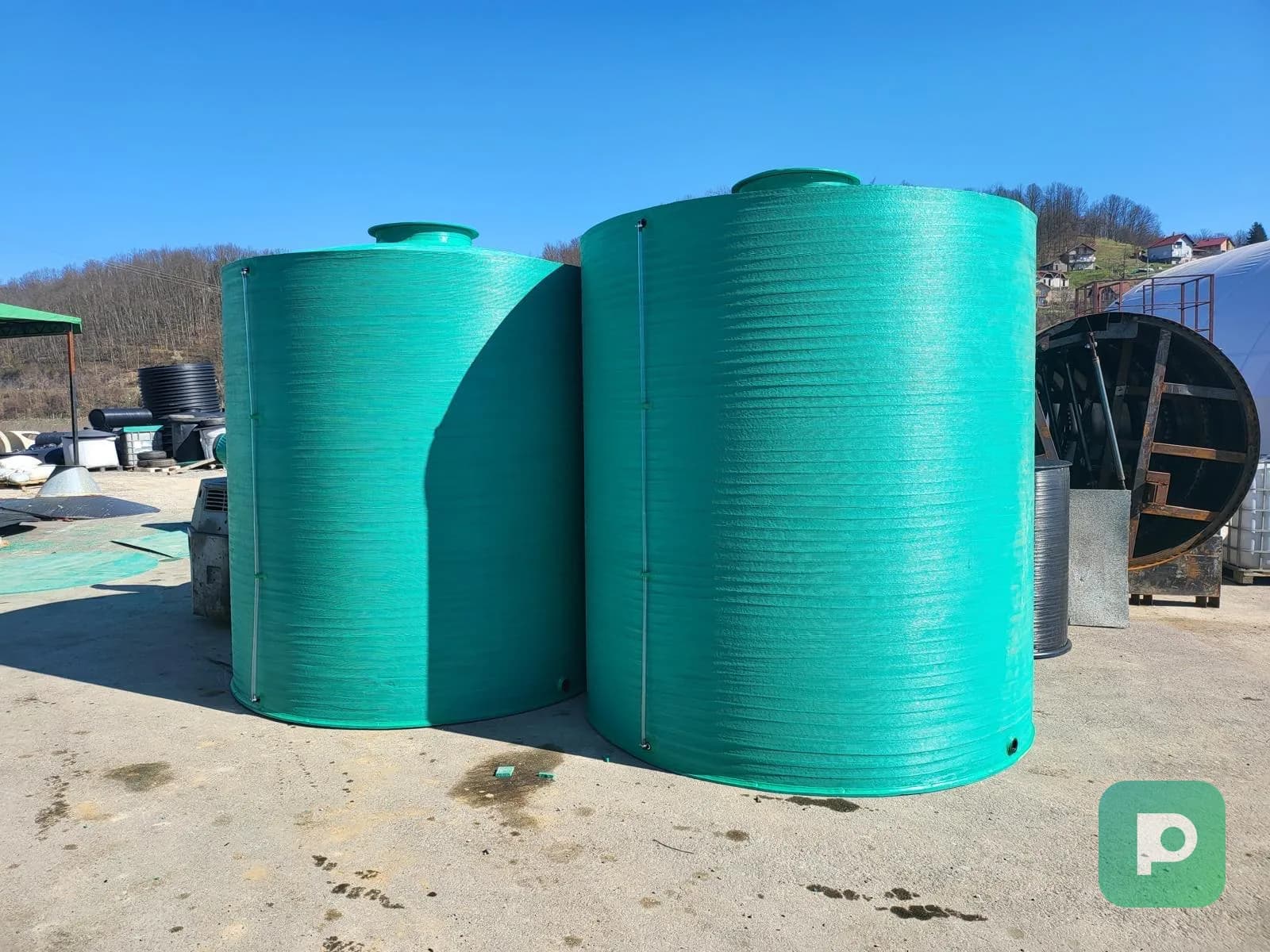 Two large green Plastopex vertical plastic tanks for water and technical liquids